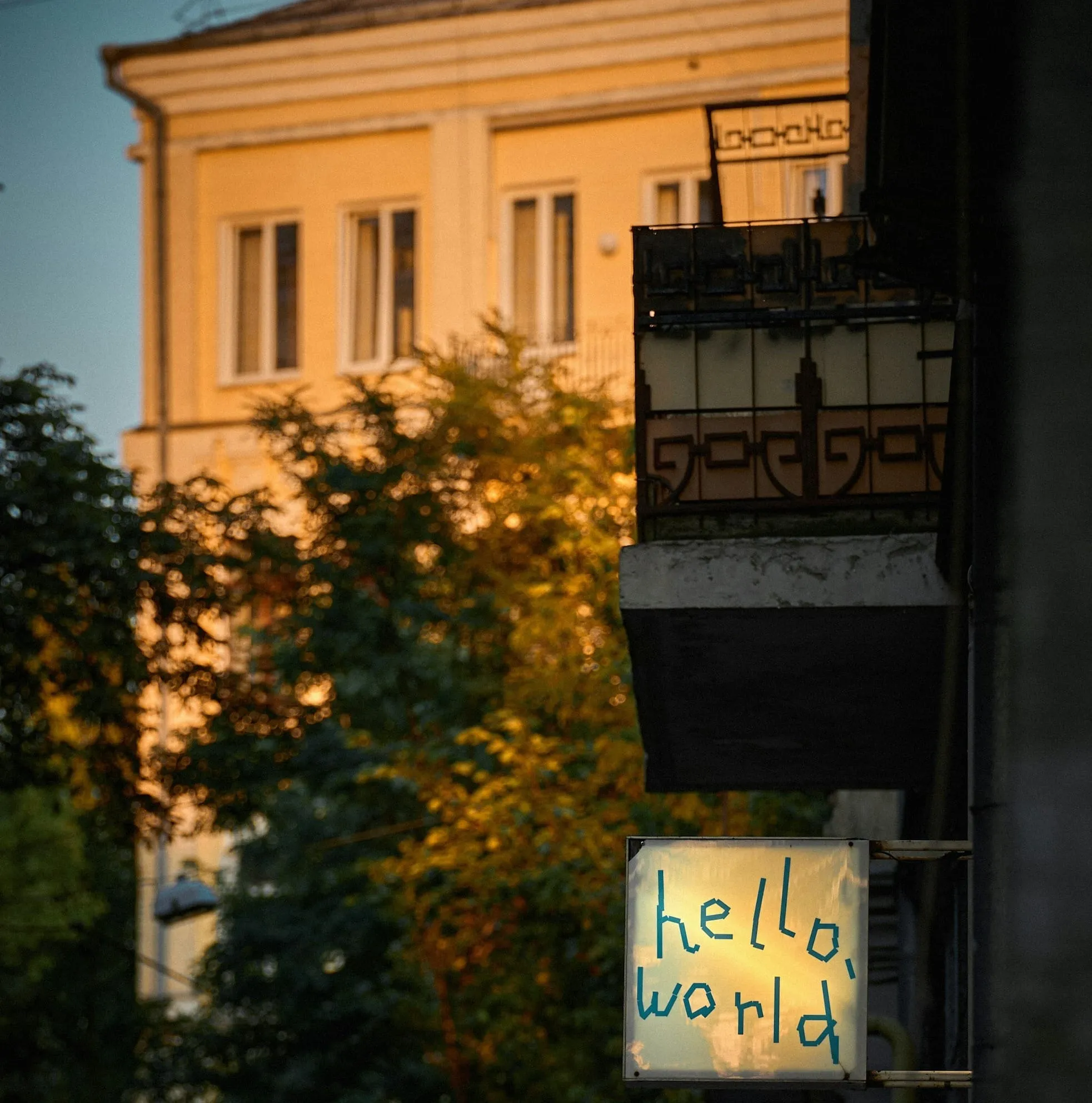 A glowing sign reading hello world on a building wall at golden hour