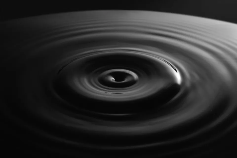 Water surface ripples showing wave patterns formed by oscillations and light reflection.