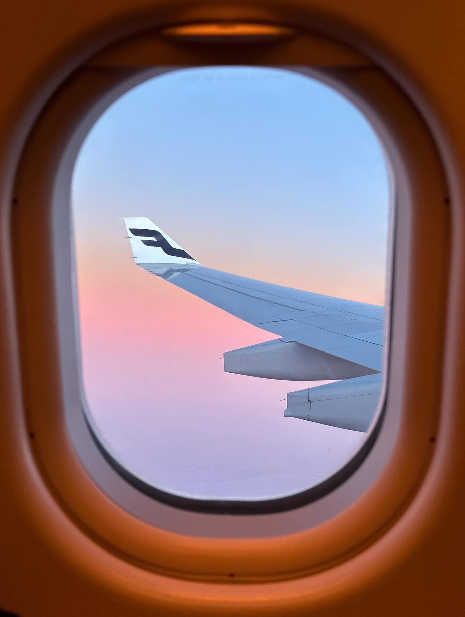 View of an airplane wing at sunset through a window.