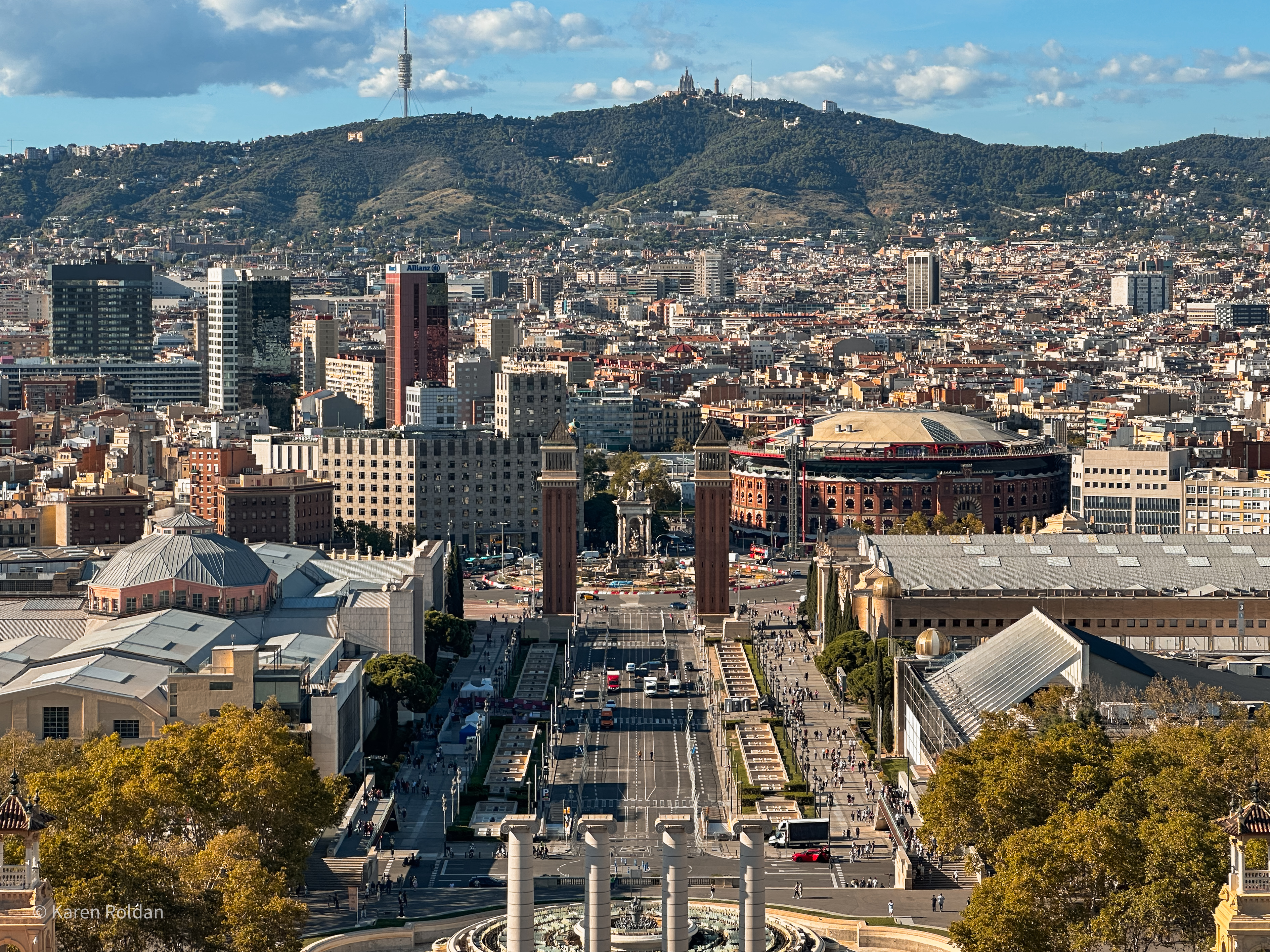 An aerial view of Barcelona looking down at Plaça d'Espanya, the Venetian Towers, and the Arenas de Barcelona bullring from the MNAC terrace.