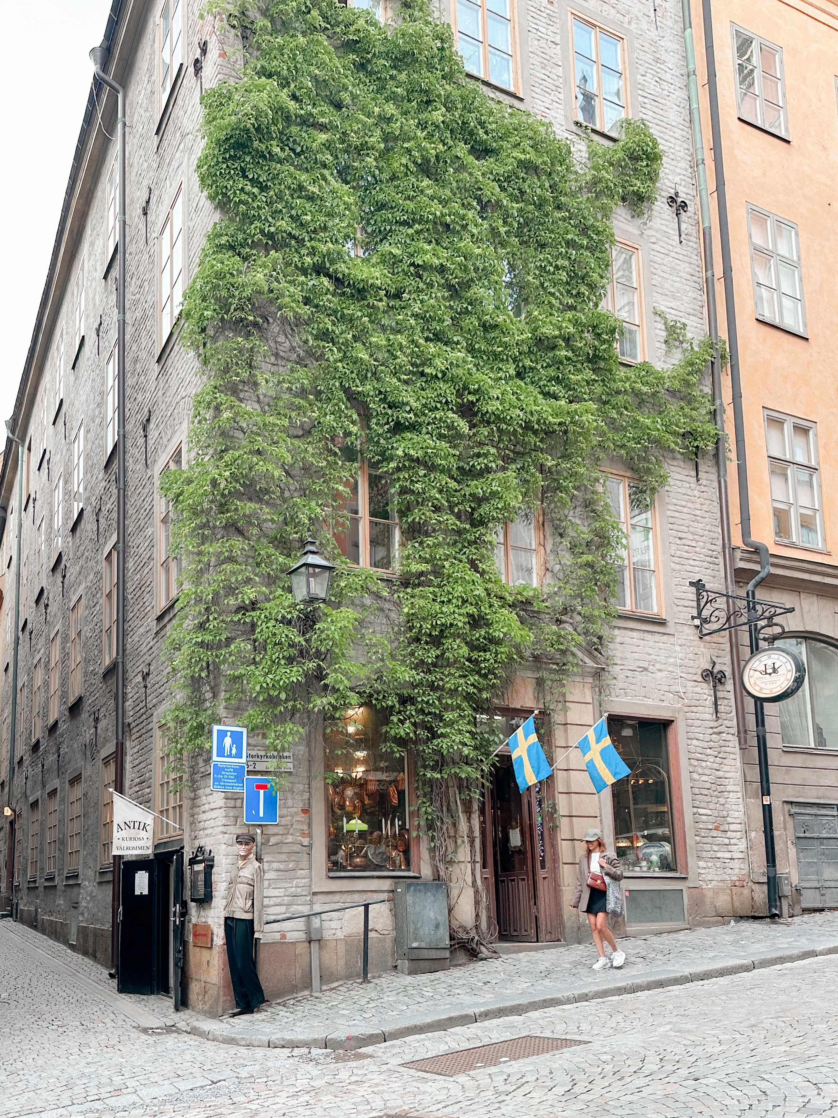 Karen Roldan standing on the cobblestone street and admiring an ivy-covered building in Gamla Stan, Stockholm, showcasing the charming and historical ambiance of the area, ideal for travelers wondering where to stay in Stockholm.