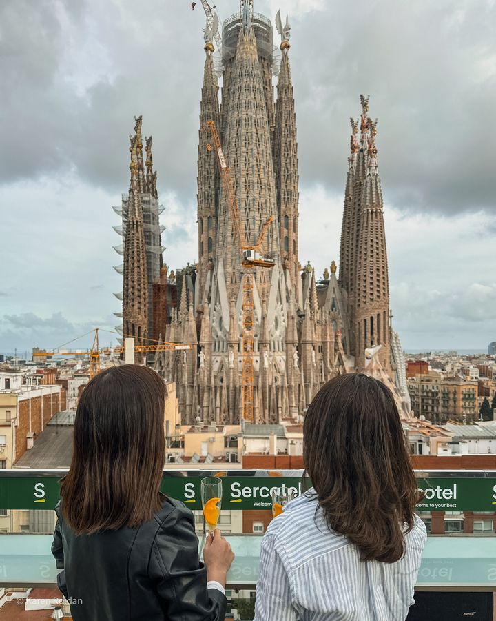 Two women having drinks at the Sercotel Rosellón rooftop bar with a close-up view of the Sagrada Familia towers in the backgr