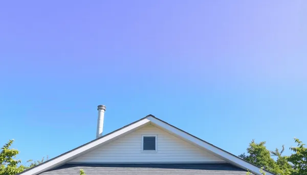 Toit de maison moderne avec des conduits de ventilation verticaux contre un ciel bleu clair