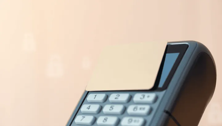 Gros plan sur une carte bancaire moderne partiellement insérée dans un terminal de paiement
