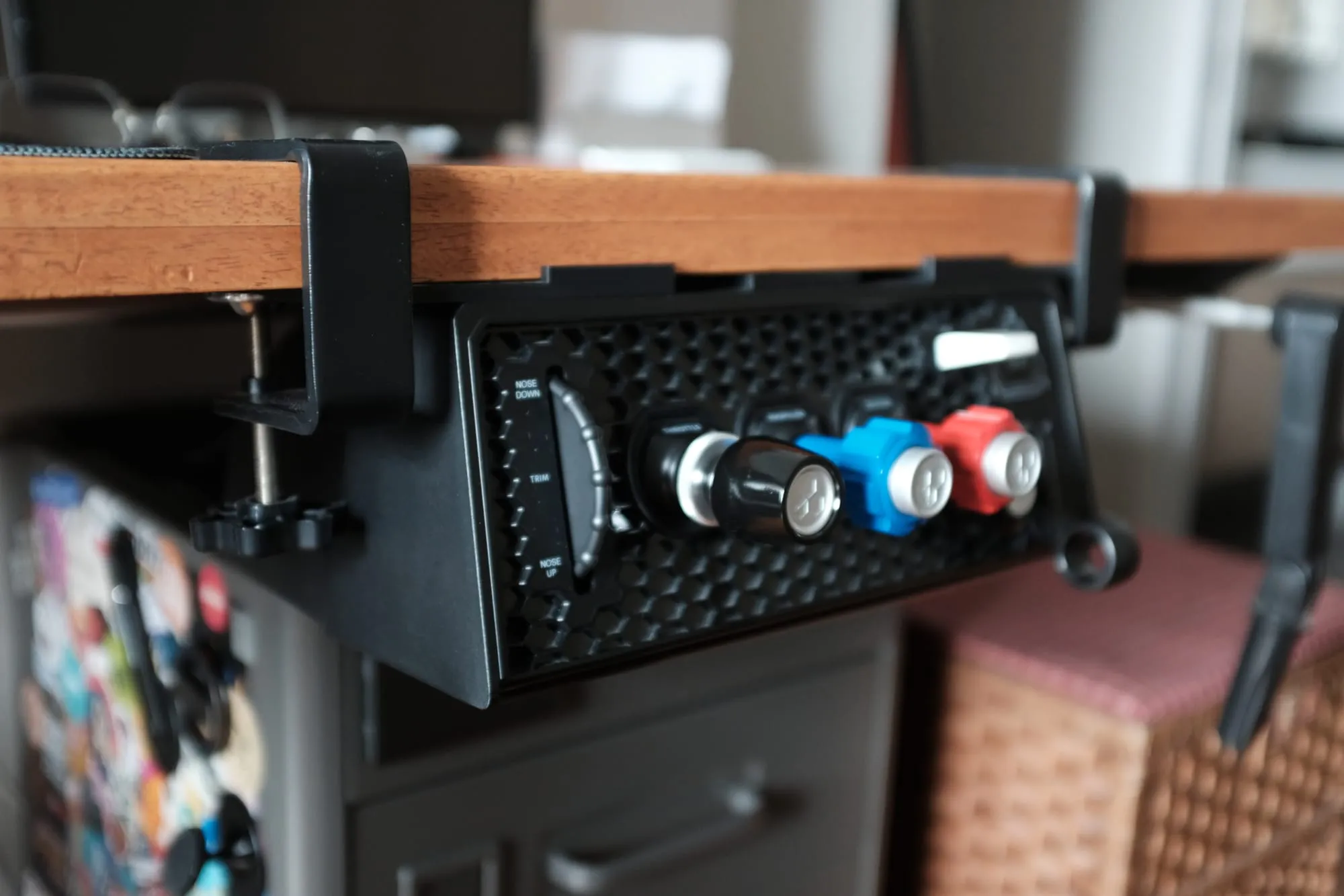 Three-quarter view of the Sierra TPM Module clamped under the front edge of a wooden desk, showing the clamp hardware and the trim wheel, vernier levers and flap toggle.