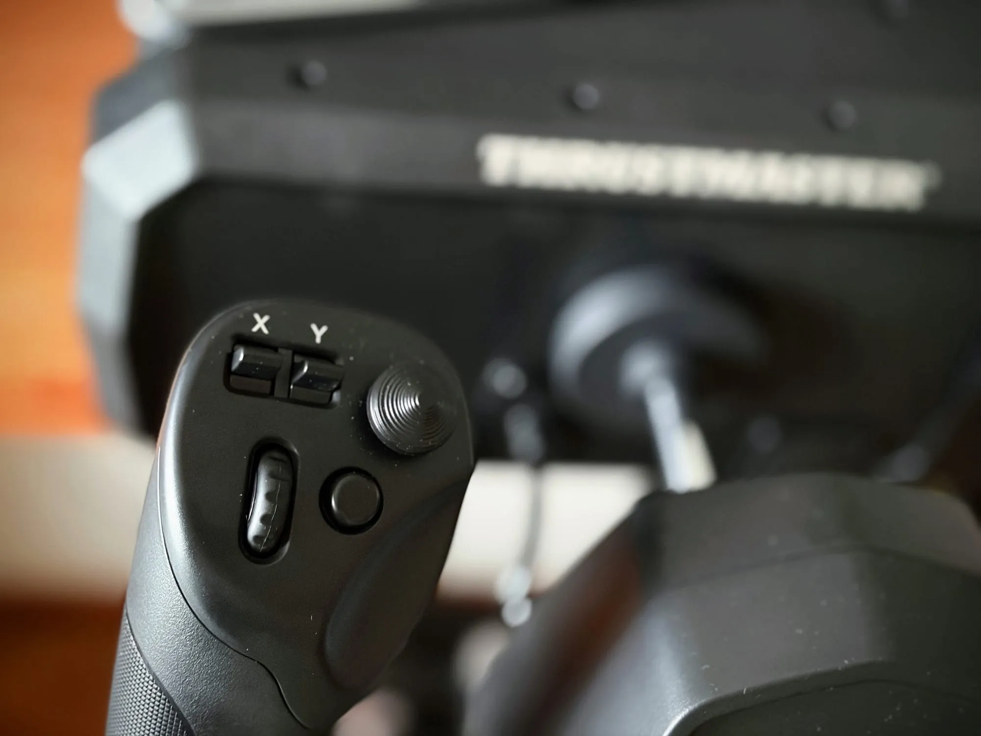 Close-up of the left grip: two rocker switches labelled X and Y, a round ridged hat switch, a slim rocker and a round button, with the steel shaft behind.