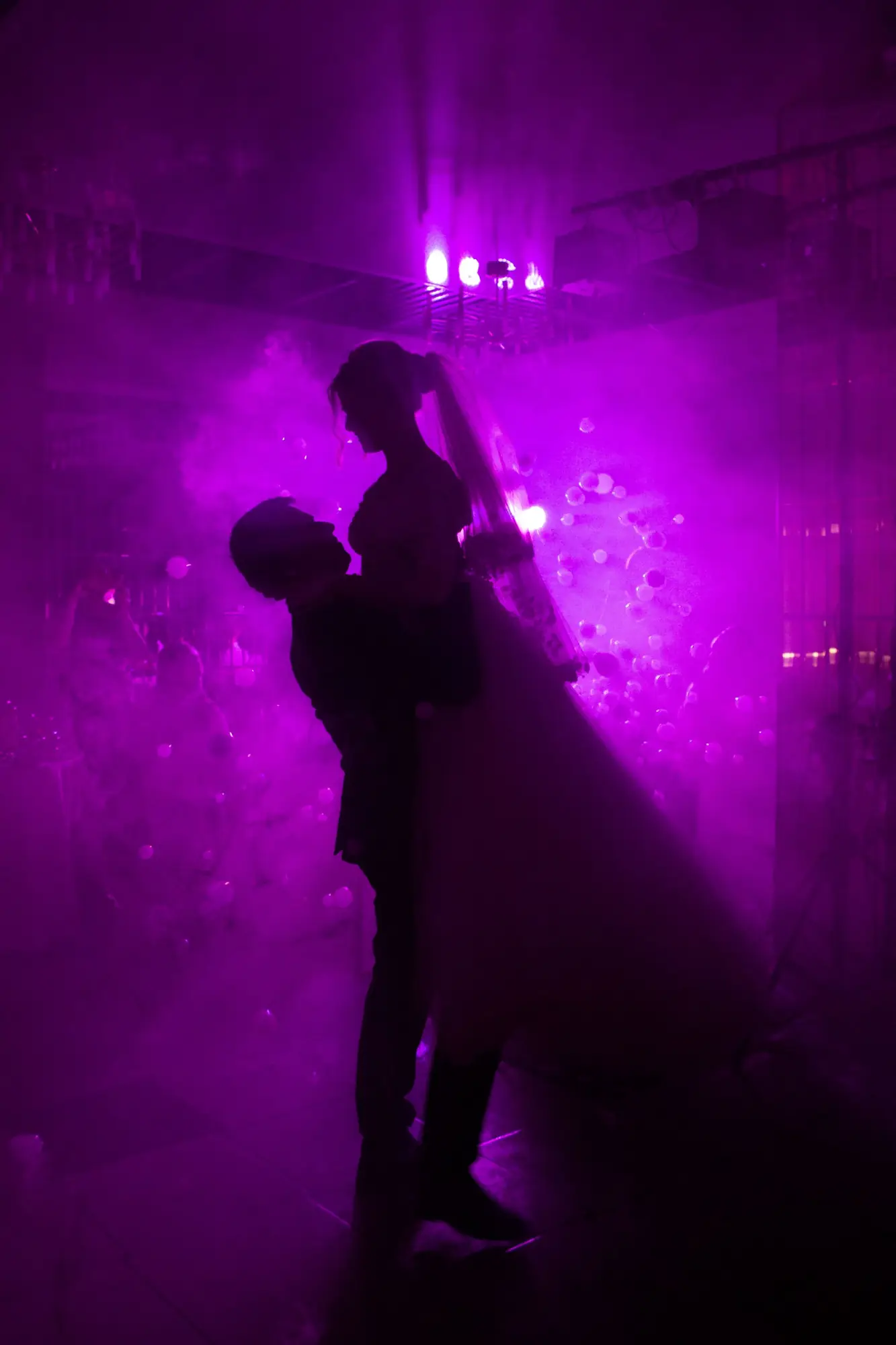 Silhouetted couple dances in vibrant purple haze, capturing a magical wedding moment.