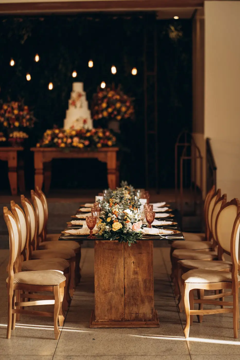 Beautifully set wedding reception table with floral arrangements and a cake at an elegant venue.