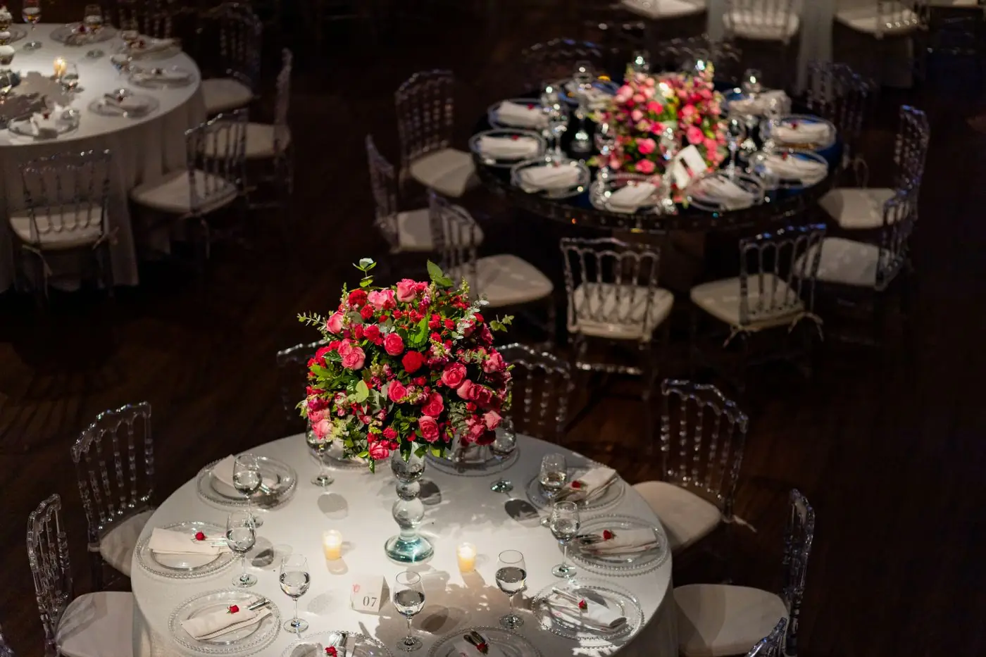 Beautifully decorated wedding reception tables with floral centerpieces and candles, creating an elegant ambiance.