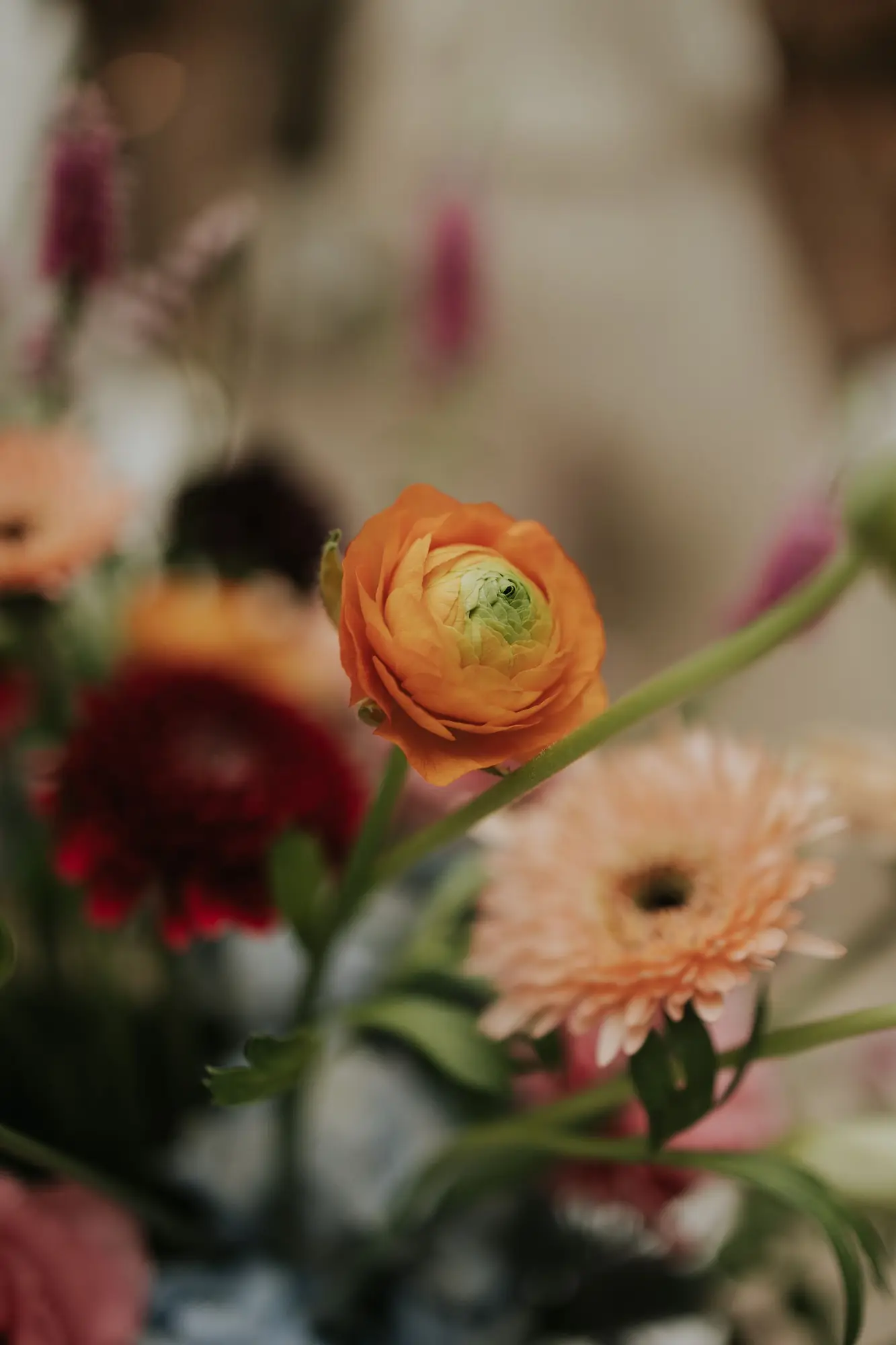 A beautiful close-up of a colorful spring flower bouquet featuring a vivid orange ranunculus.
