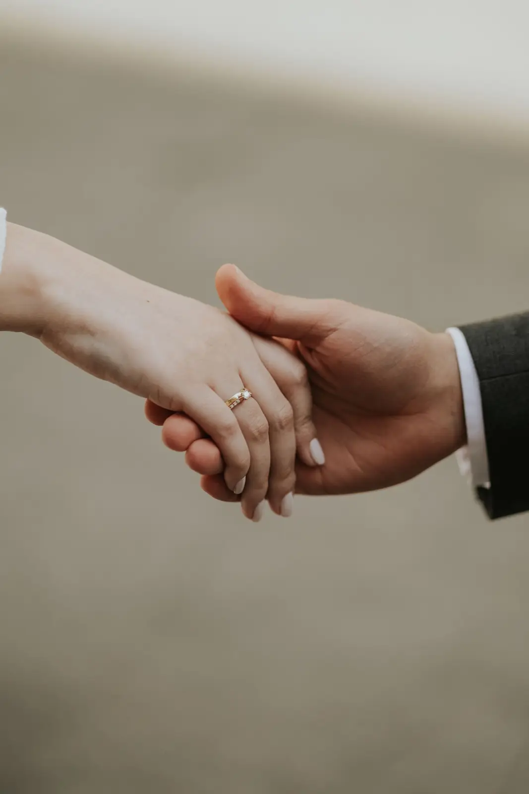 Close-up of a couple holding hands showcasing wedding rings, symbolizing love and commitment.