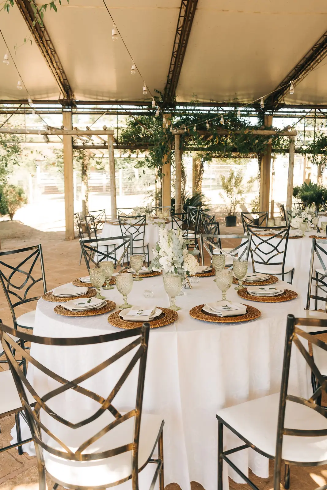 Beautifully arranged tables with elegant decor for an outdoor wedding reception under a canopy.