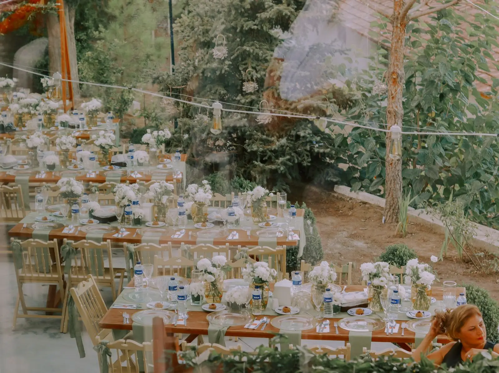 Elegant outdoor wedding reception with rustic wooden tables and floral decor.