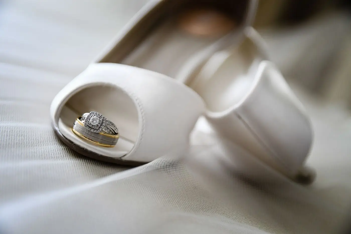Close-up of bridal shoes with diamond wedding rings, highlighting elegance and romance.