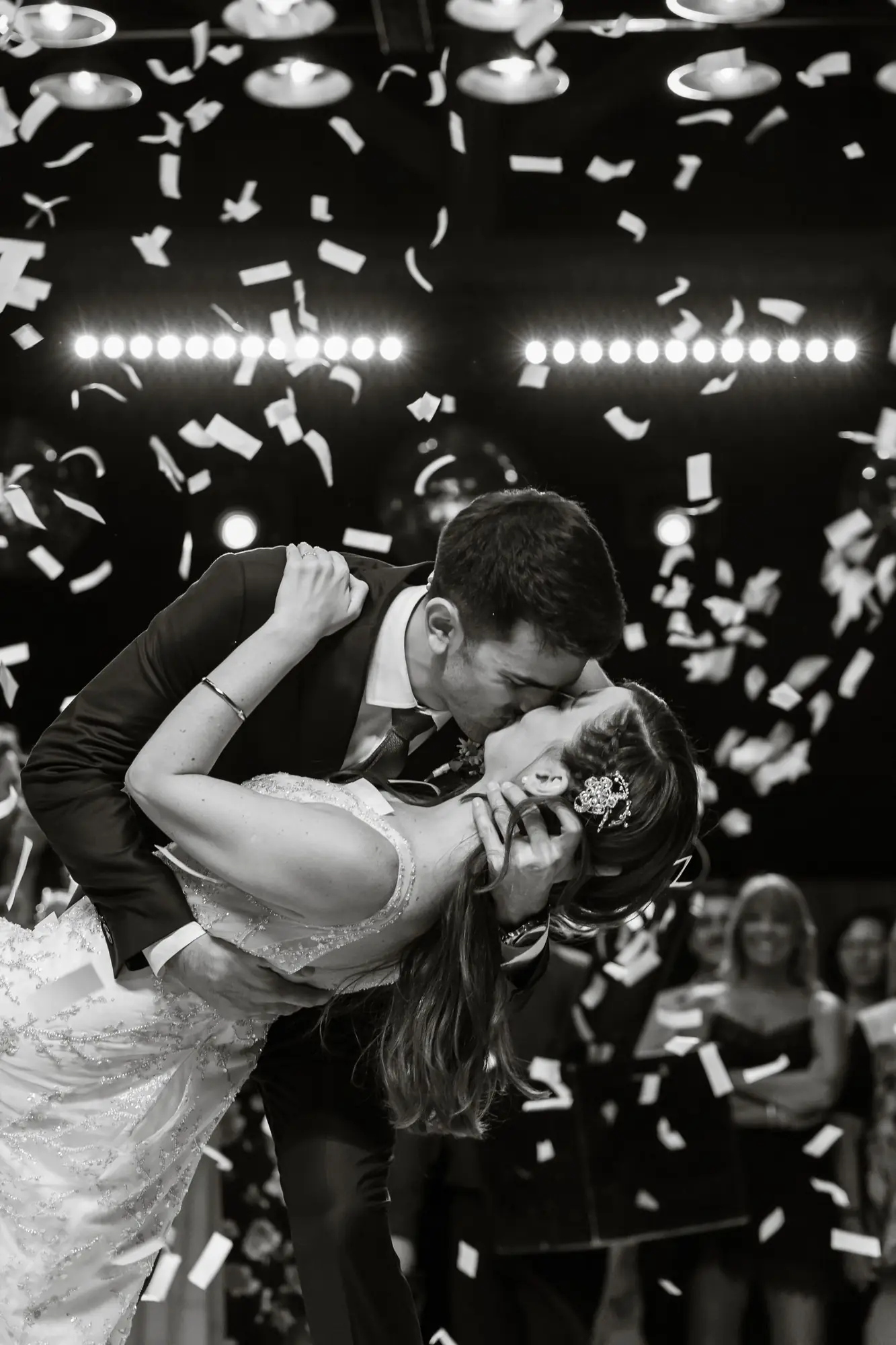 Newlyweds share a romantic kiss under confetti at their wedding reception.