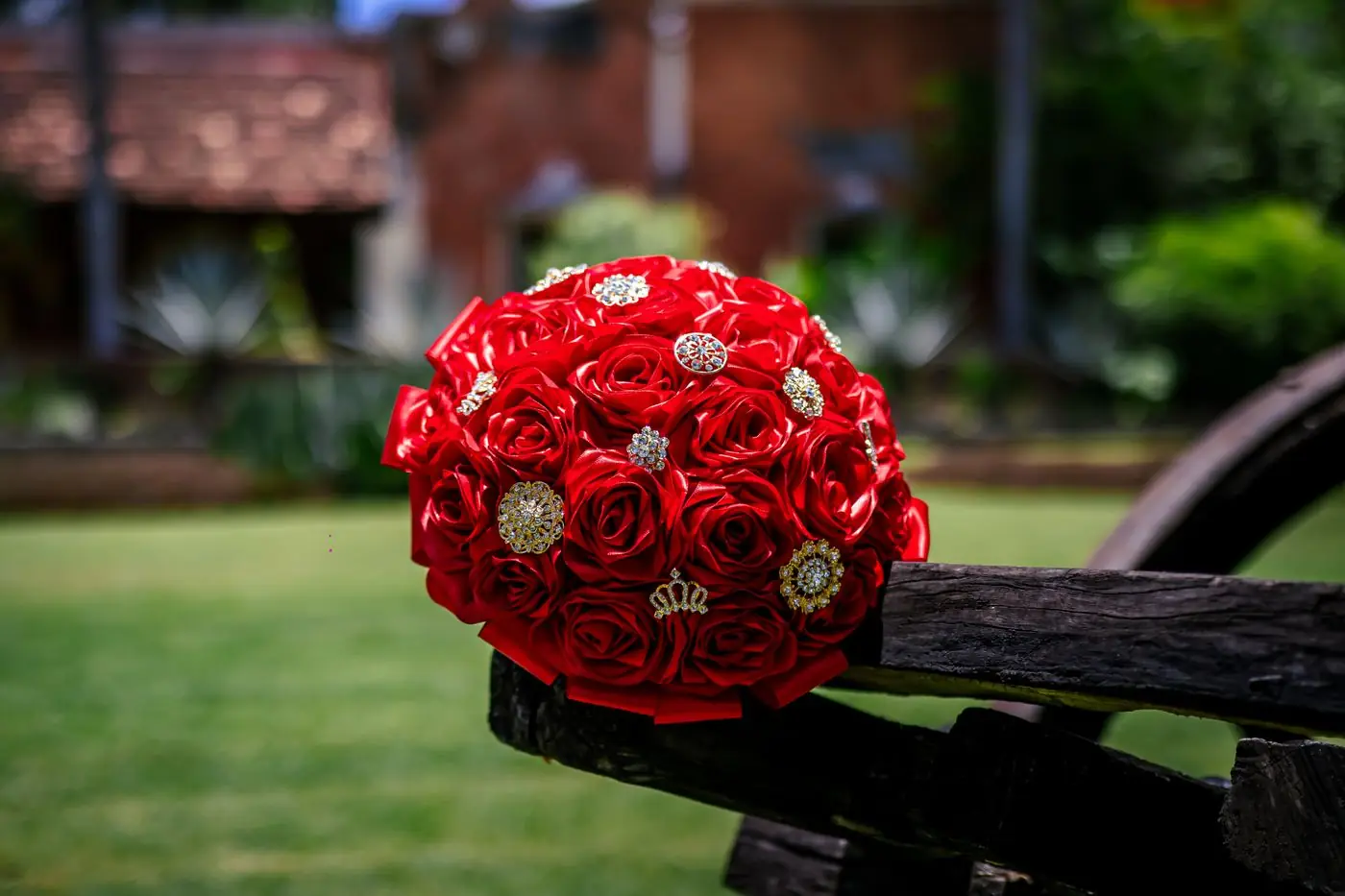 Vibrant red rose bouquet adorned with jewels in a scenic garden setting.