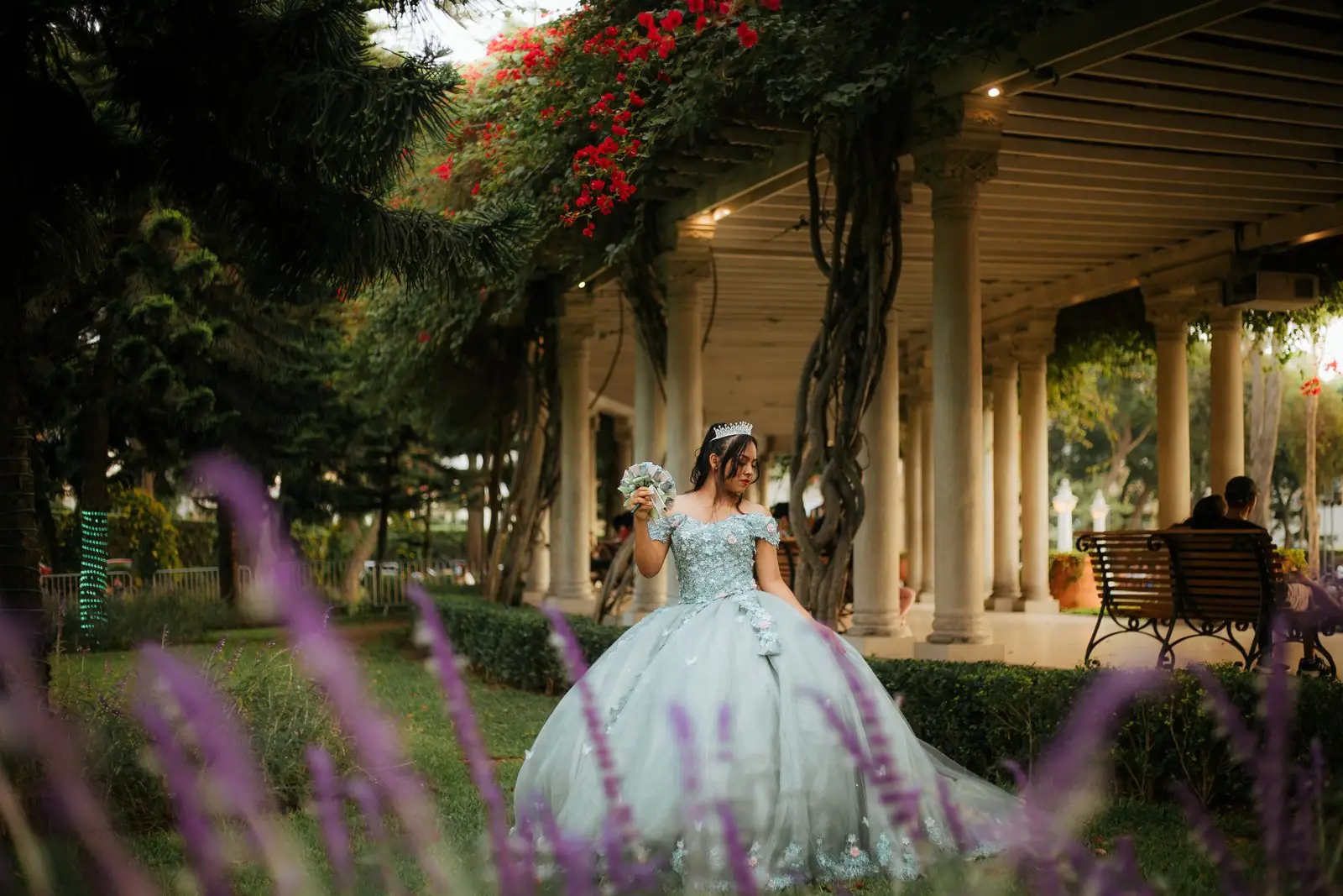 A bride in an elegant dress stands in a lush garden setting in Lima, Peru.
