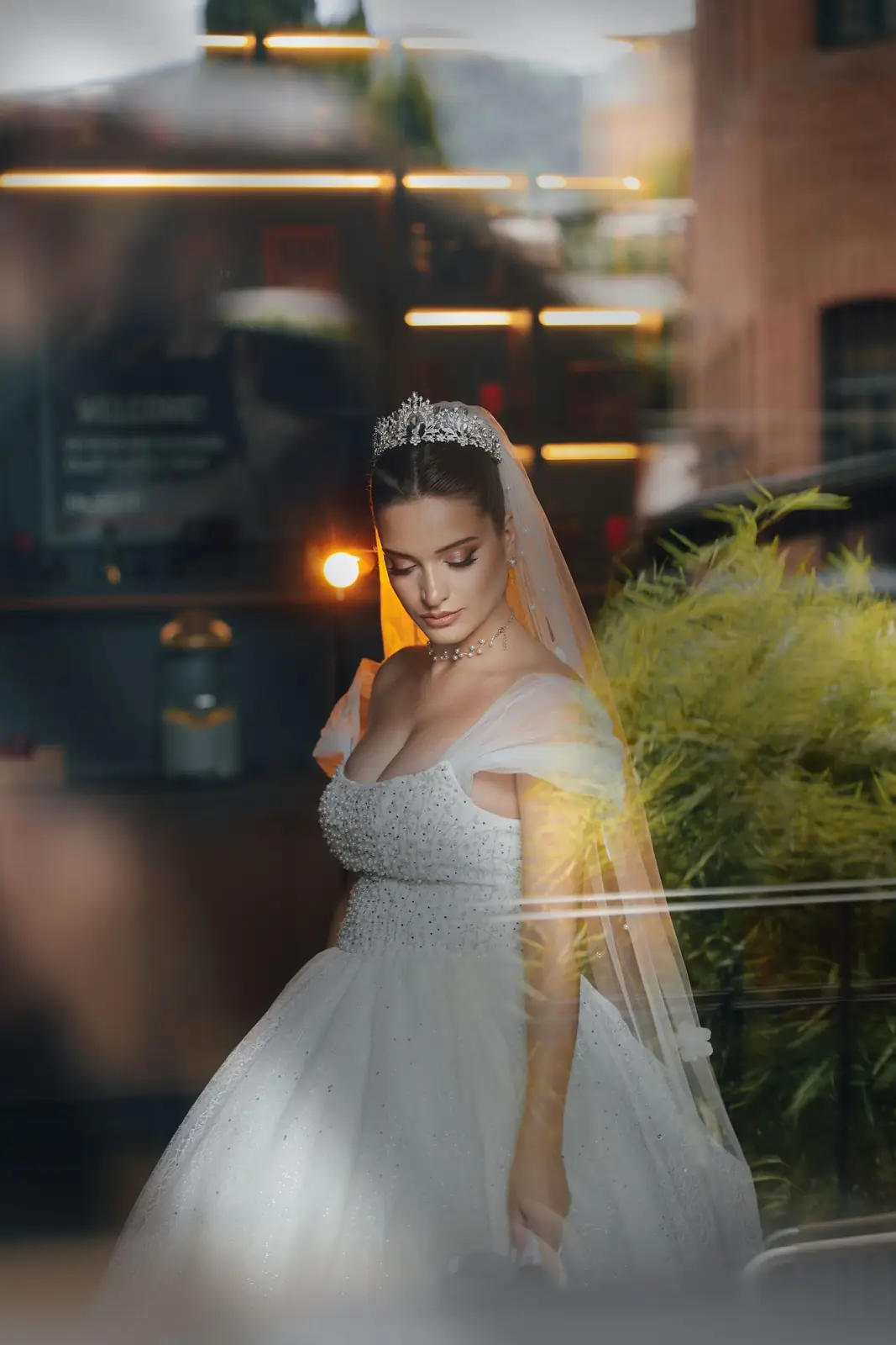 Beautiful bride in a stunning gown gazing down in an intimate indoor setting.