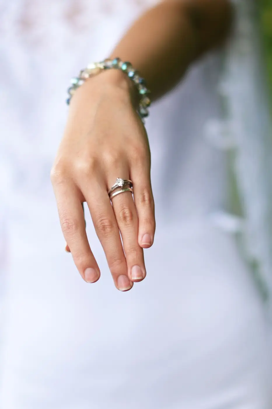 Close-up of a bride's hand displaying wedding rings and bracelet, highlighting elegance.