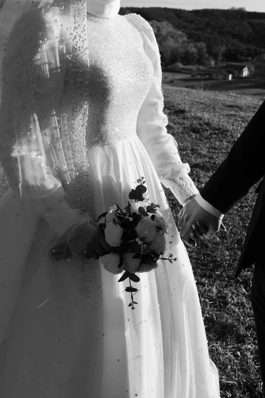 Bride and groom holding hands outdoors in black and white image.