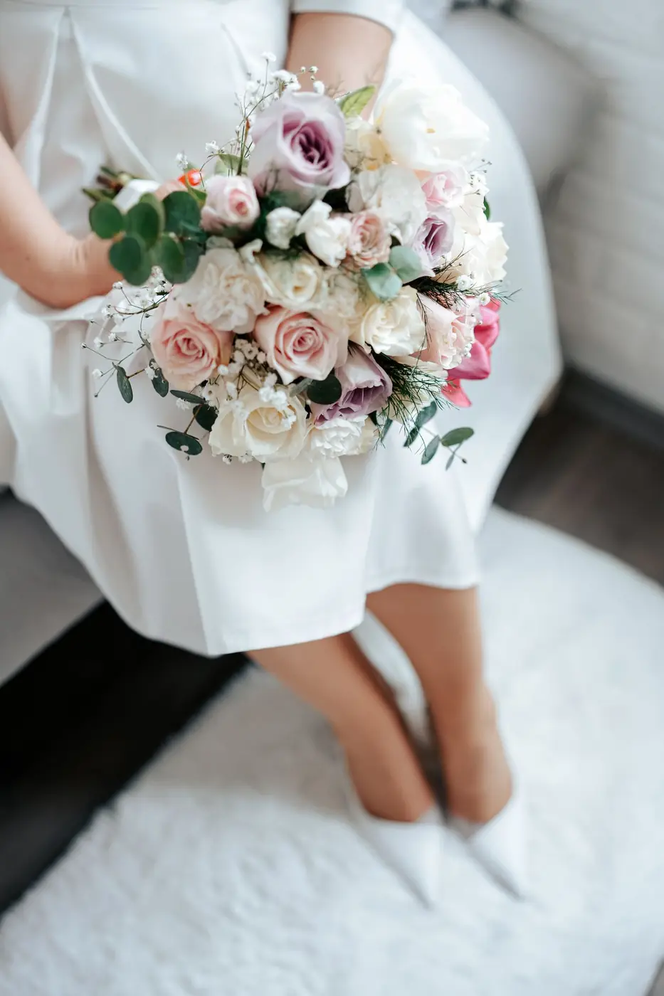 A bride elegantly holding a bouquet of roses, showcasing a charming and romantic wedding moment.