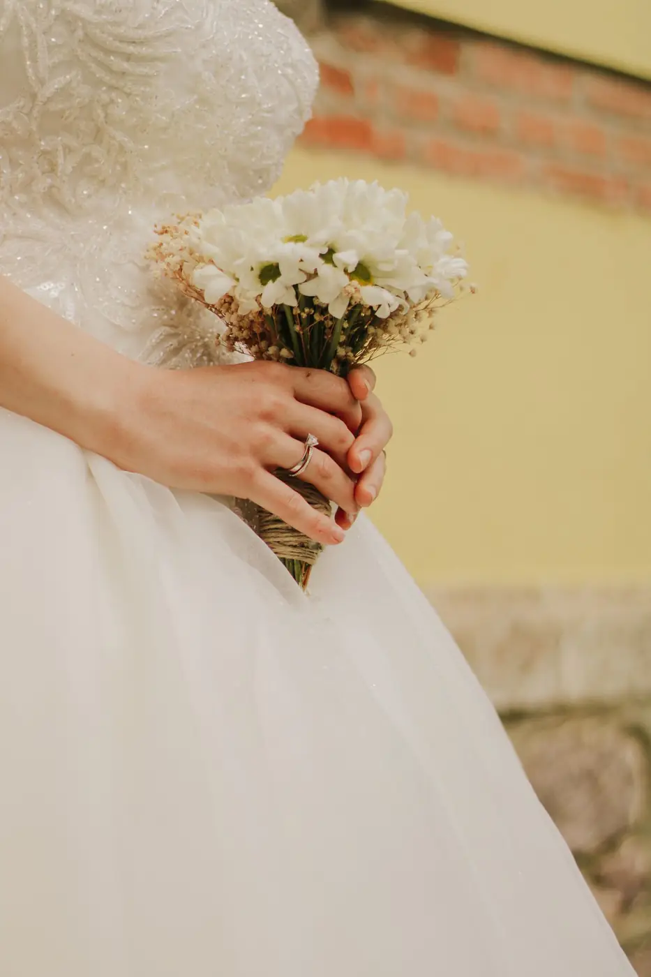 Close-up of a bride holding a white bouquet, showcasing wedding details and elegance.