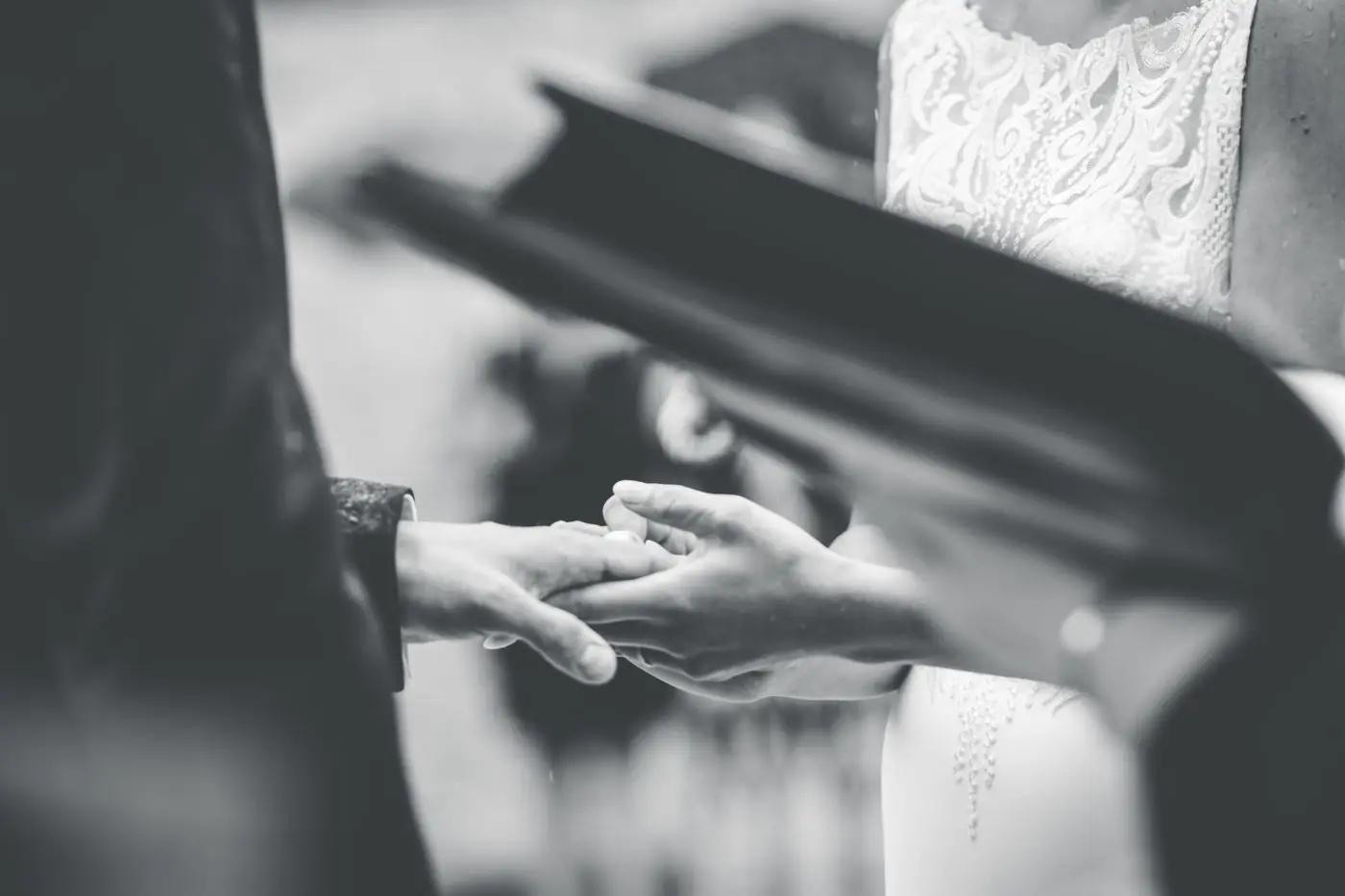 A touching black and white photo capturing the moment a bride and groom exchange rings during a wedding ceremony.