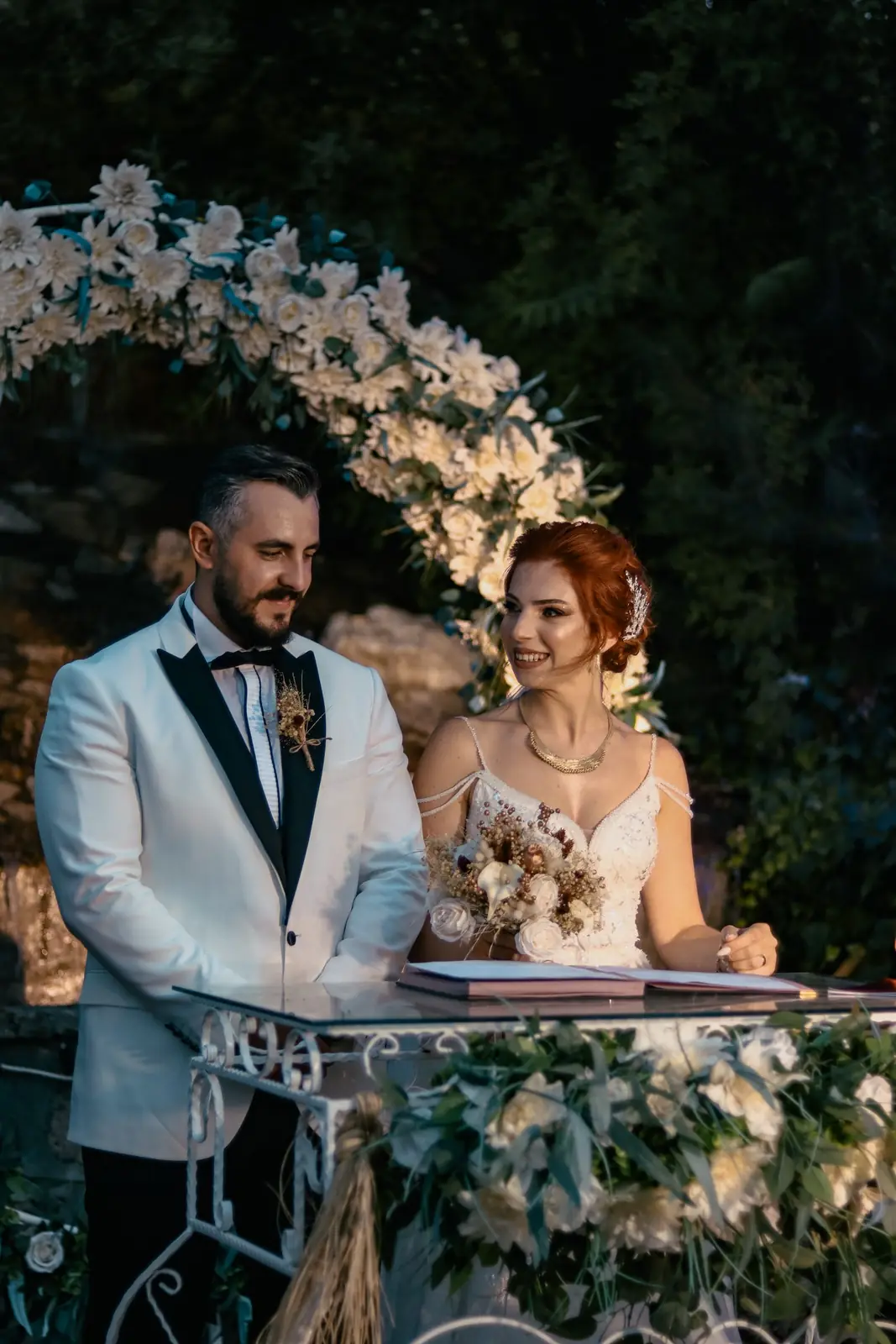 Beautiful couple during their wedding ceremony surrounded by floral decorations and natural lighting.
