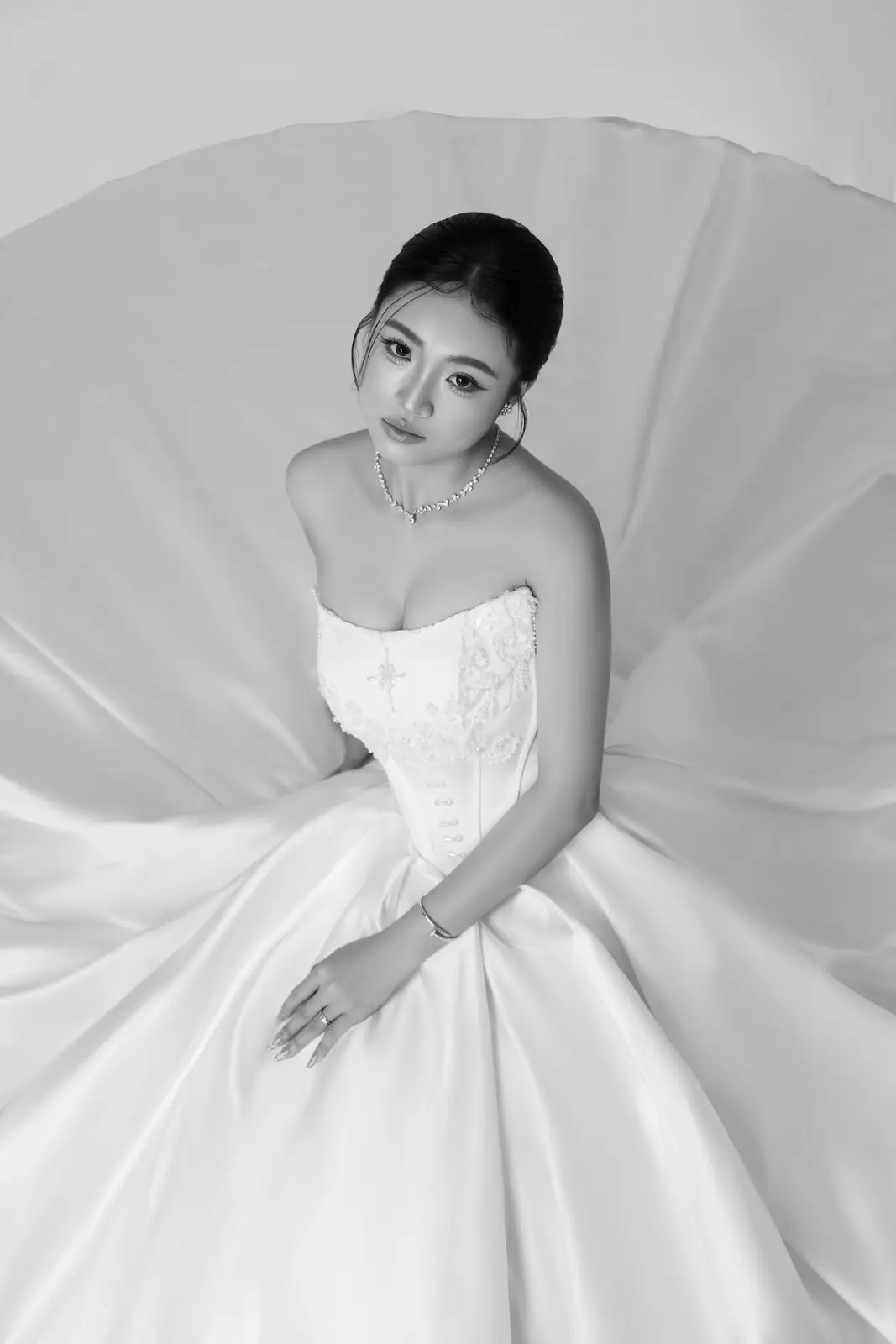 Black and white portrait of a bride in an elegant gown, serene and poised.