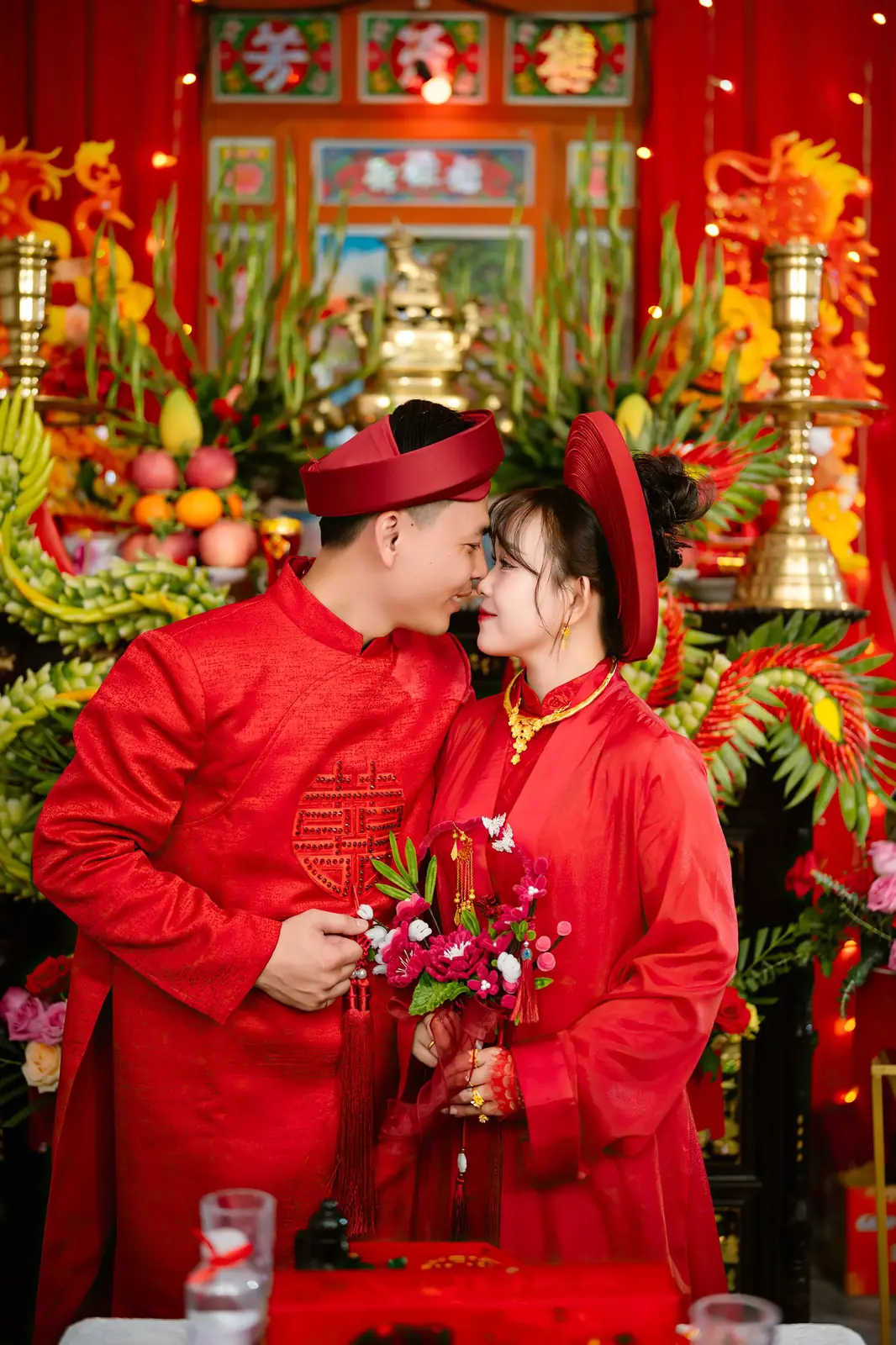 A couple in traditional Vietnamese attire shares a tender moment during their wedding ceremony in Ho Chi Minh City.