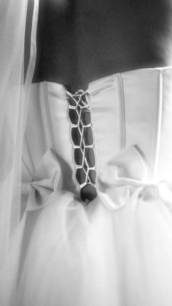 Close-up of a bride in a white dress with pearl details, hands gracefully clasped.