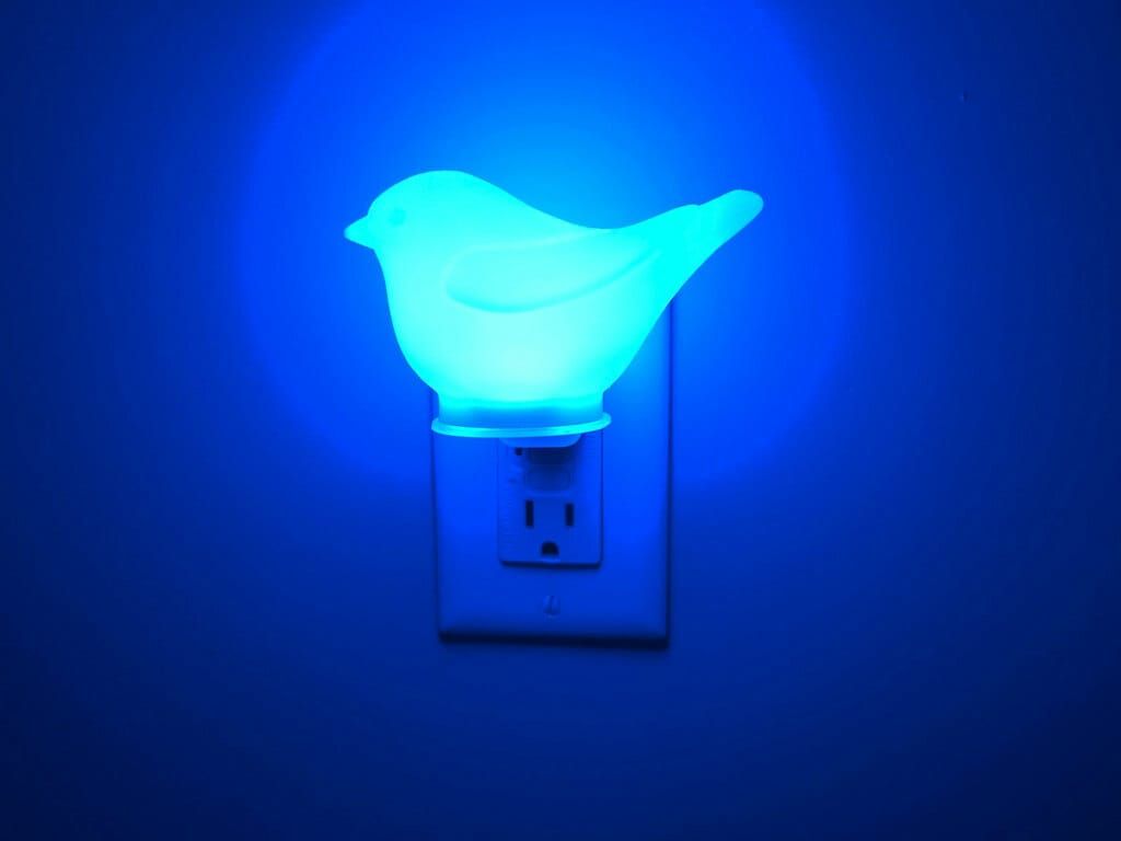 a lit froste blue canary night light plugged into a north american standard GFCI wall outlet