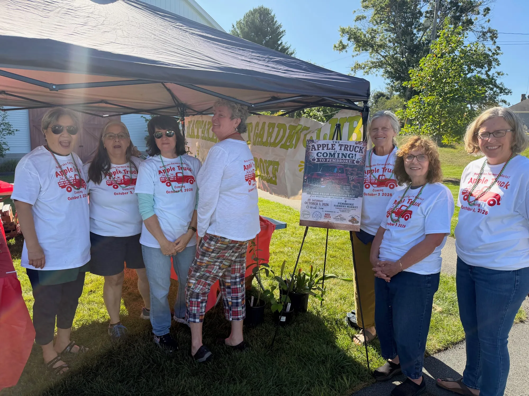 Members of the Mattakeesett Garden Club sport t-shirts advertising their upcoming apple sale at the Pembroke Farmer's Market.