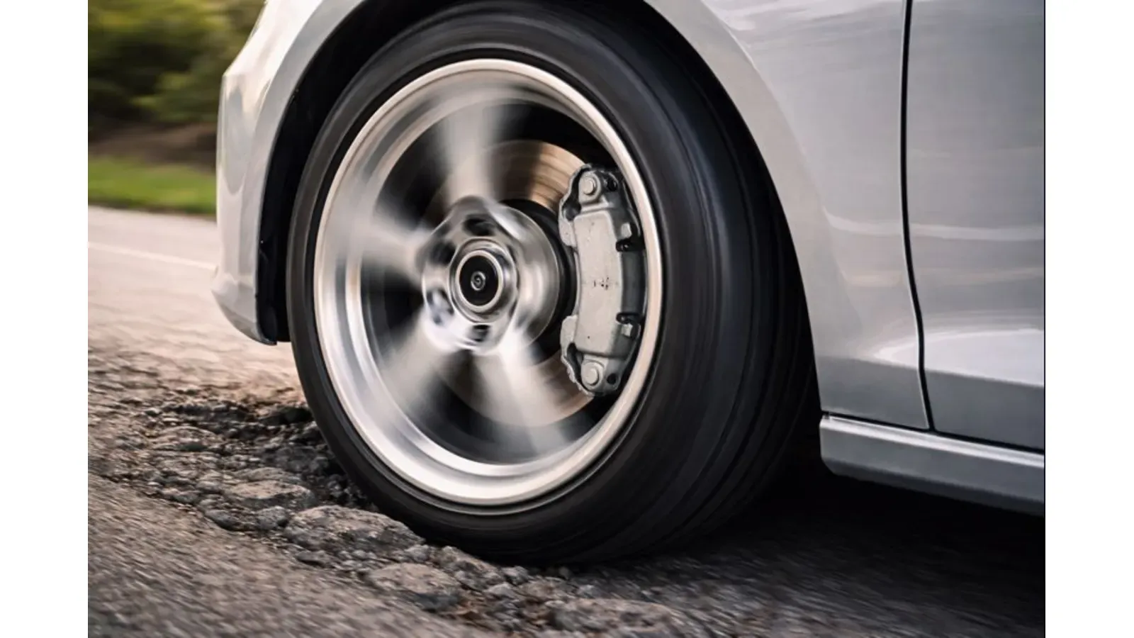 A rotating car wheel with visible brake disc and caliper, illustrating how worn brake or bearing components can create grinding or humming noises.