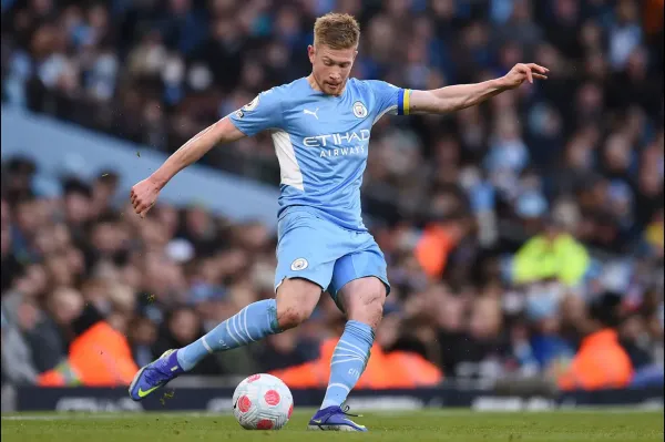 Manchester City midfielder striking the ball during a professional football match in a packed stadium