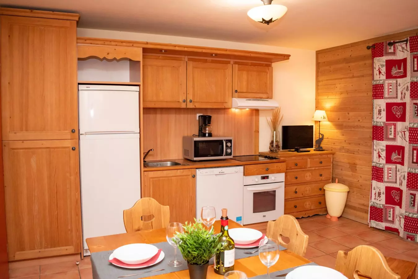 Cuisine équipée au style montagnard avec meubles en bois, coin repas convivial et électroménager complet 