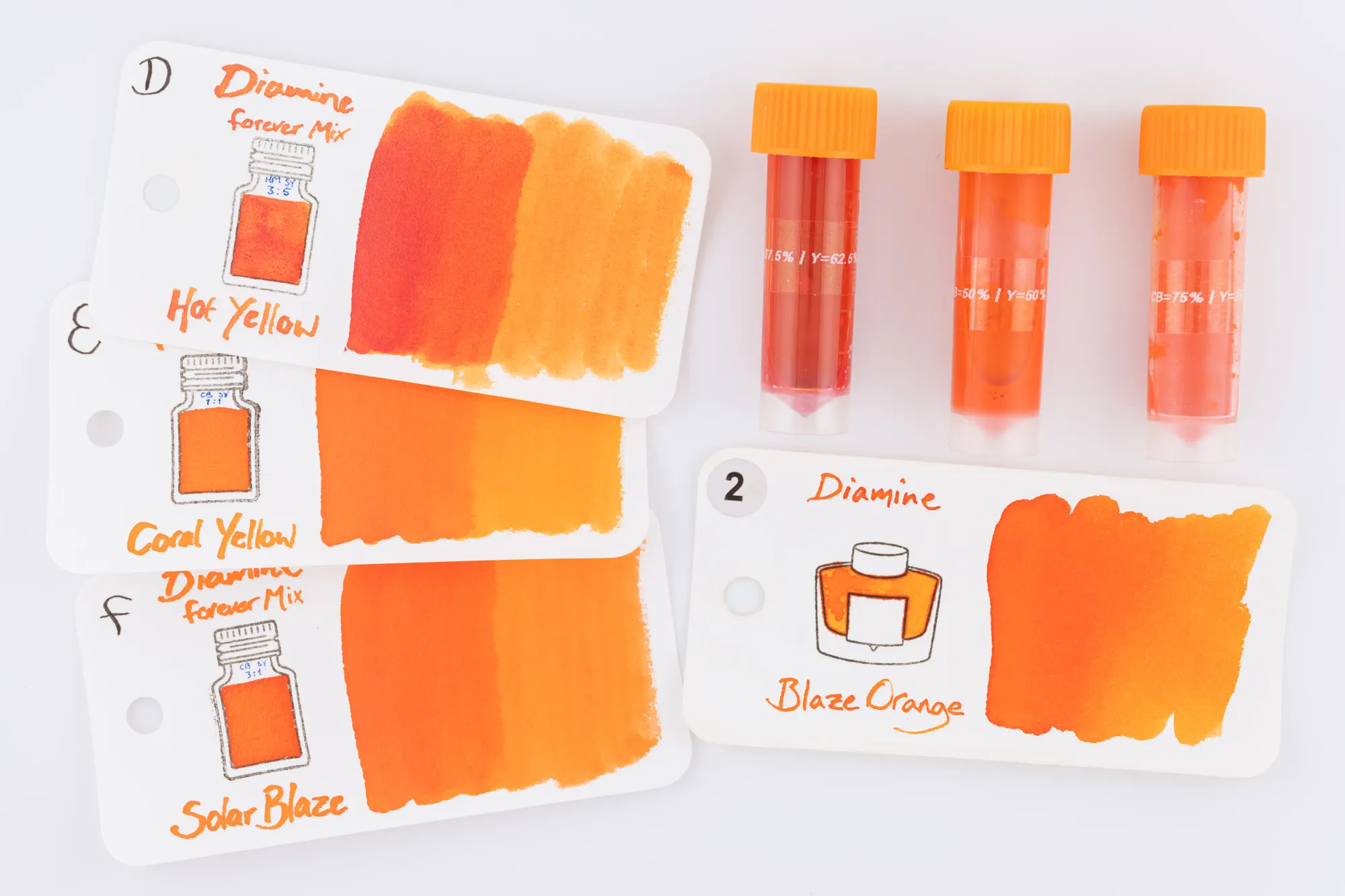 Overhead photo of 3 5ml ink vials filled with different orange mixed inks, along with 4 ink swatches of the 3 mixes and Diamine Blaze Orange.