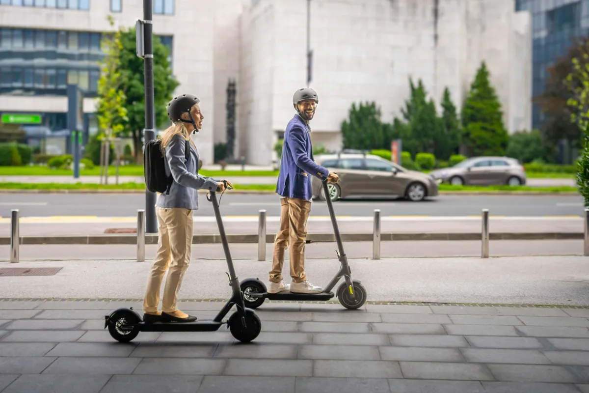 Couple souriant conduisant une trottinette électrique
