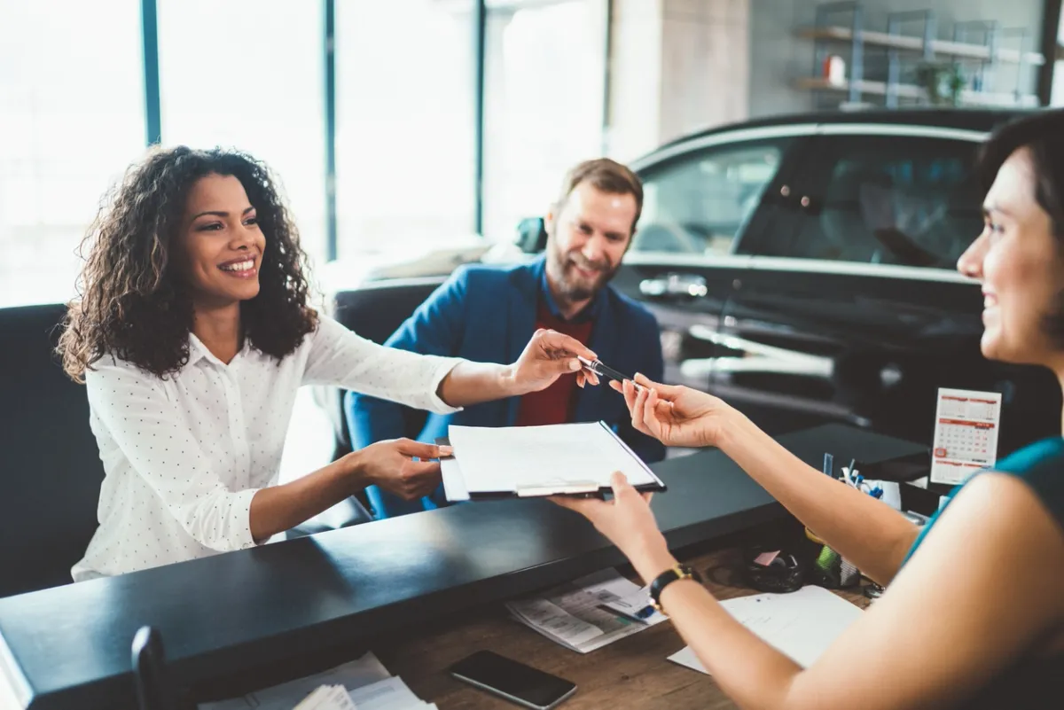Un couple louant une voiture après avoir effectué toutes les vérifications nécessaires et signé le contrat