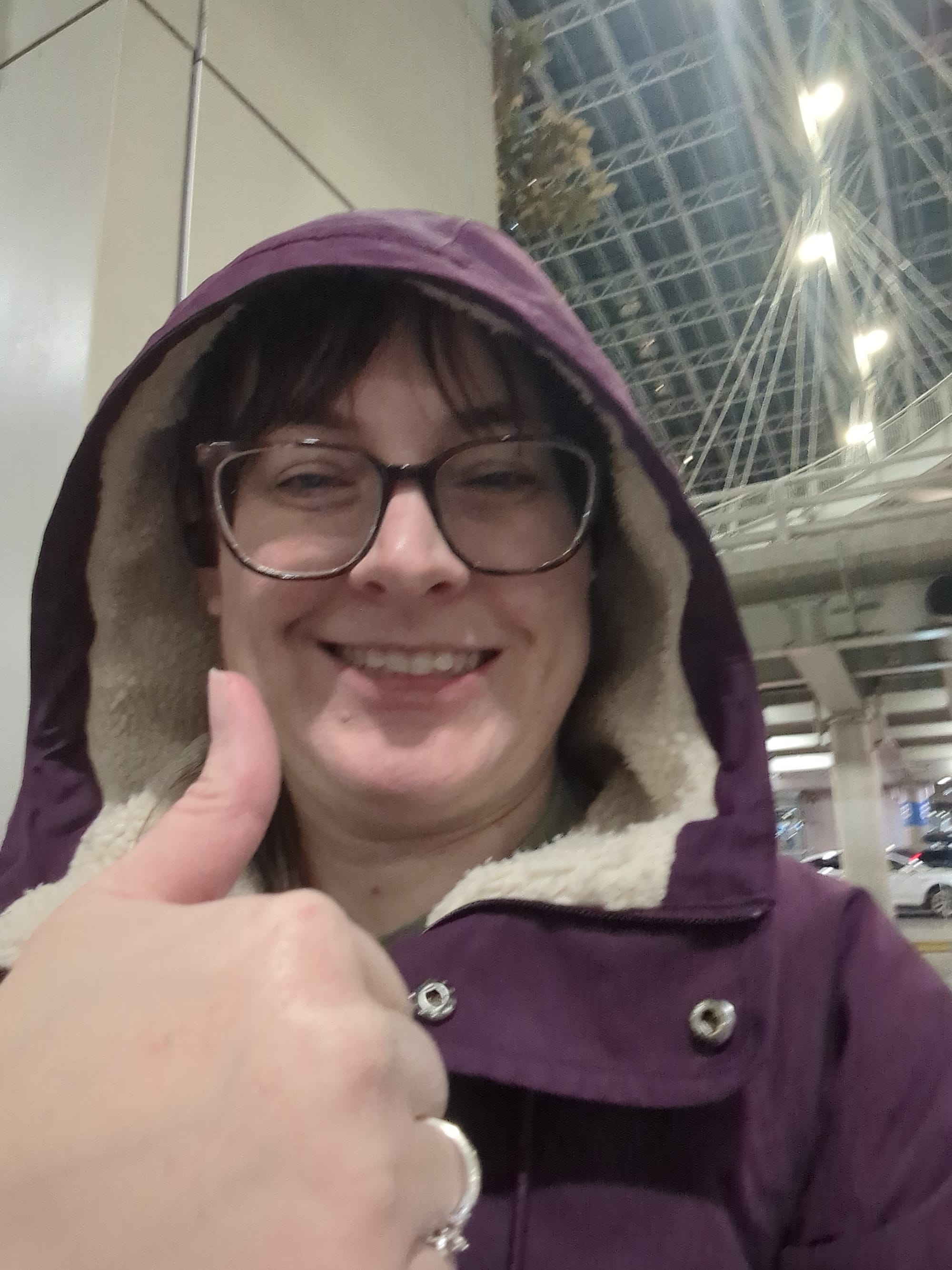The author sitting in front of an airport, looking tired and sick but smiling and giving a thumbs up
