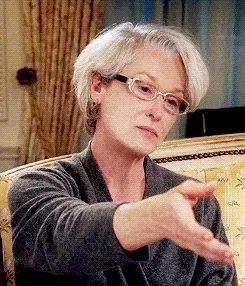 A GIF of Miranda Priestly holding out a hand imperiously and saying "By all means, move at a glacial pace"
