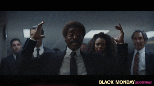 A GIF from "Black Monday" showing Don Cheadle, as the main character, looking agitated and astonished and saying "Oh my god! Outrageous and amazing!" Other characters smile in the background.