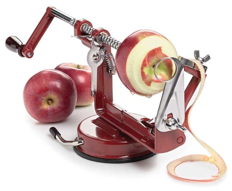 Photo of a hand-cranked device that is spiraling an apple into a blade that peels and slices it