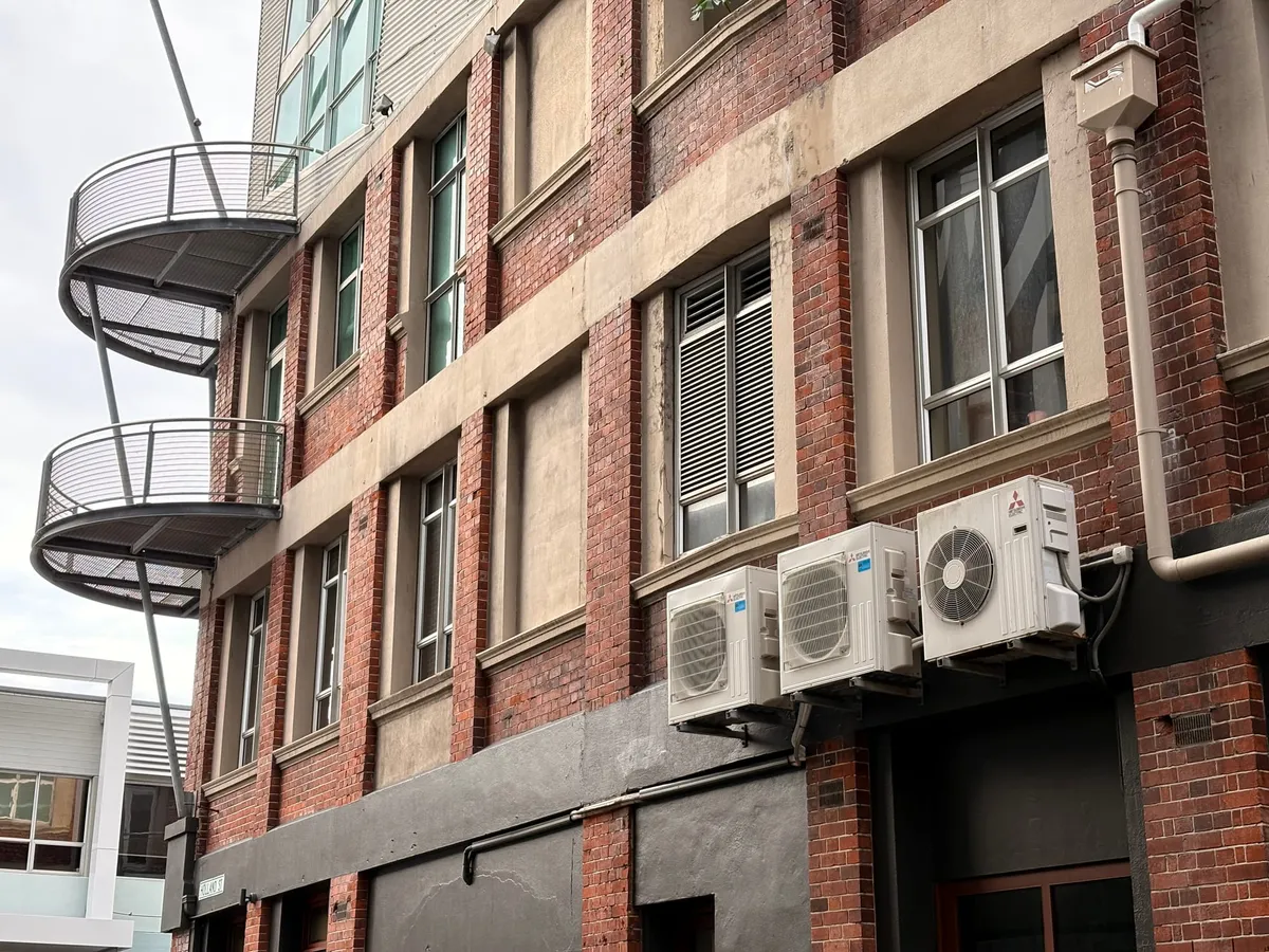 Three external heat pump units on a Tory Street building