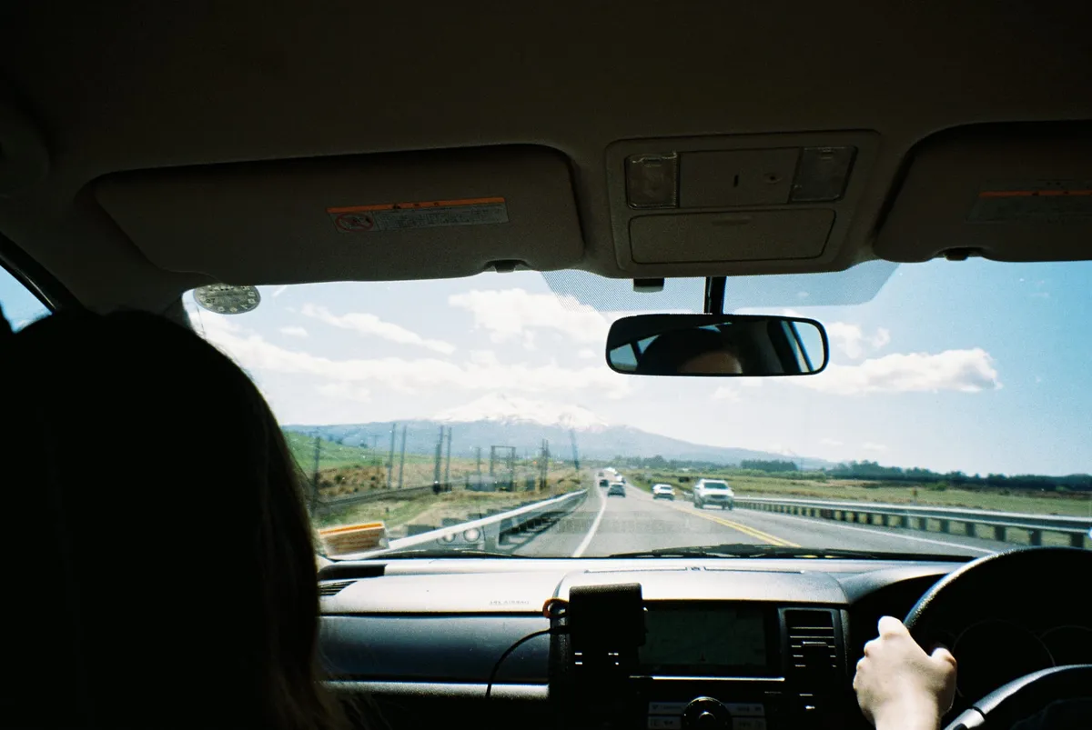 A photo from inside the back of a car going along a state highway. Ruapehu is in the background.