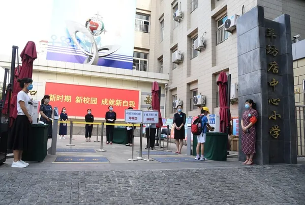 Des enseignants attendent le retour des élèves à l'école primaire centrale de Yangfangdian dans l'arrondissement de Haidian à